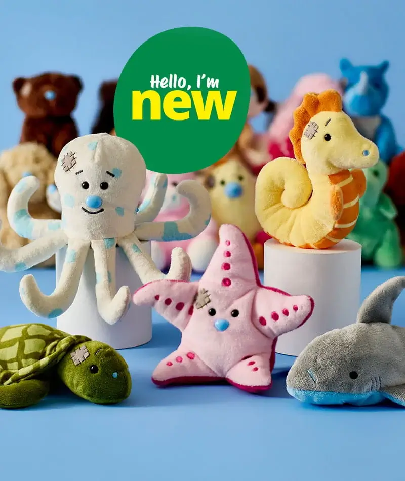 A group of soft plush sea animal toys arranged on a blue background, including an octopus, starfish, turtle, seahorse, and shark, with a green badge reading hello, I’m new.